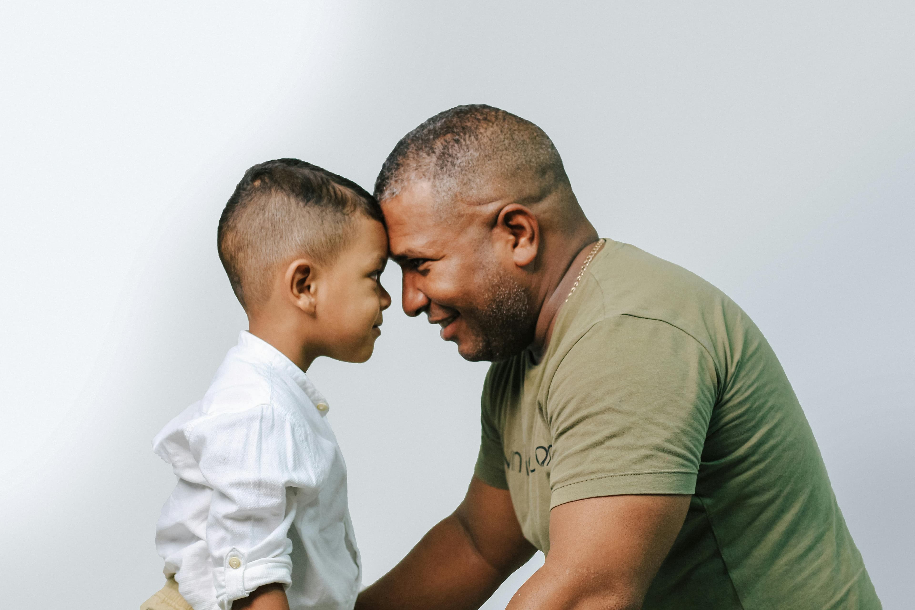 Father and young son smiling and with foreheads pressed together making eye contact