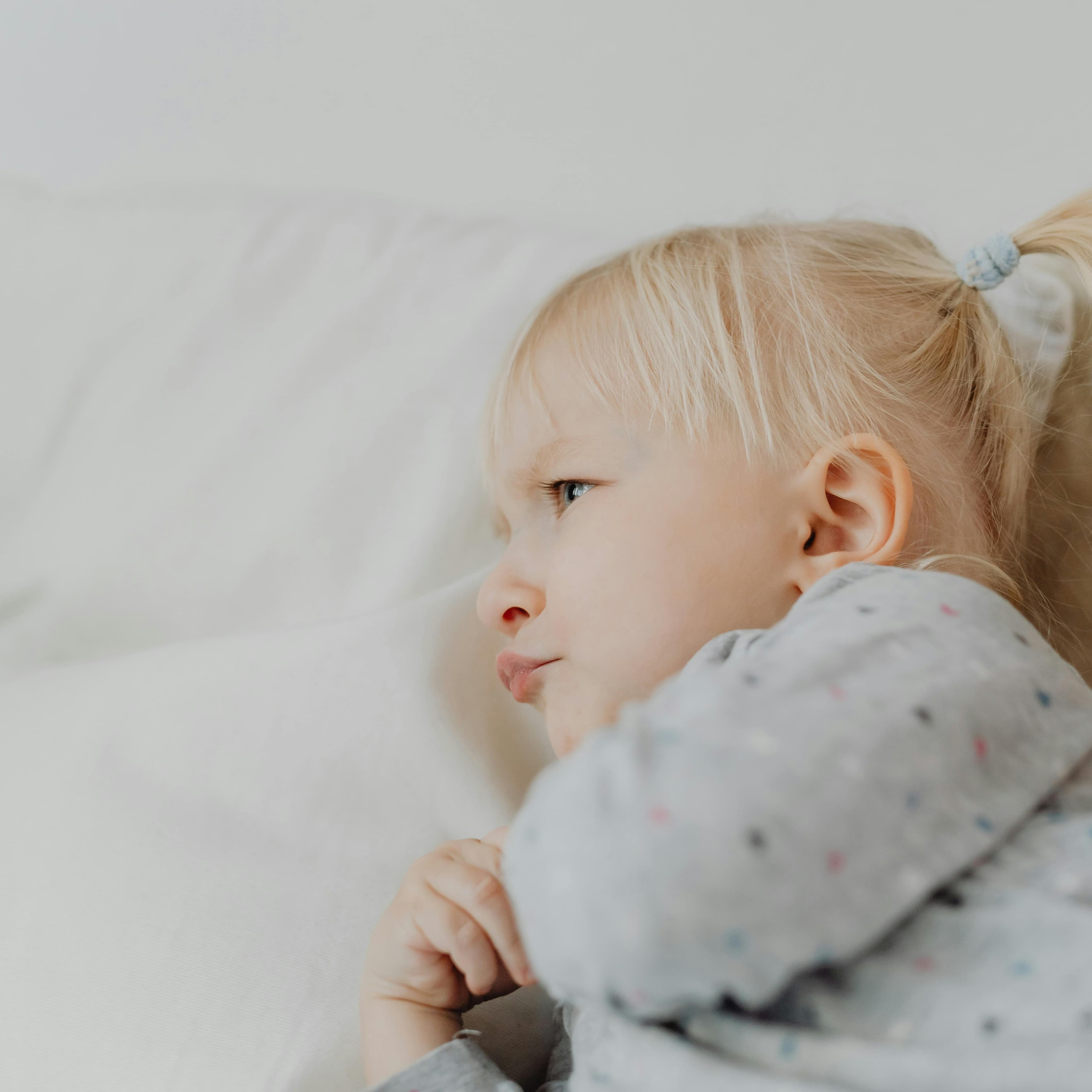 Toddler laying on her side and frowning