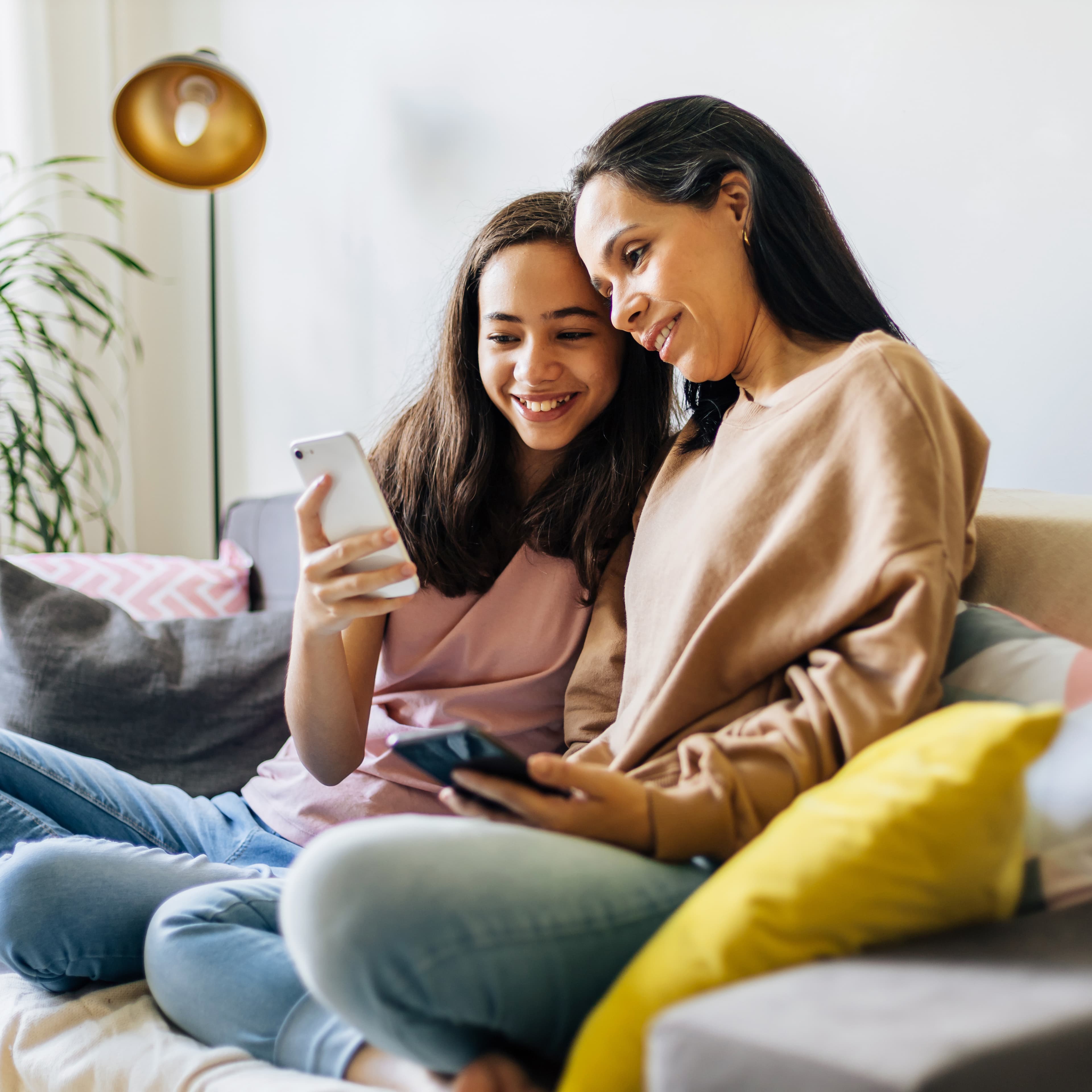 Mother and Daughter with phones on couch