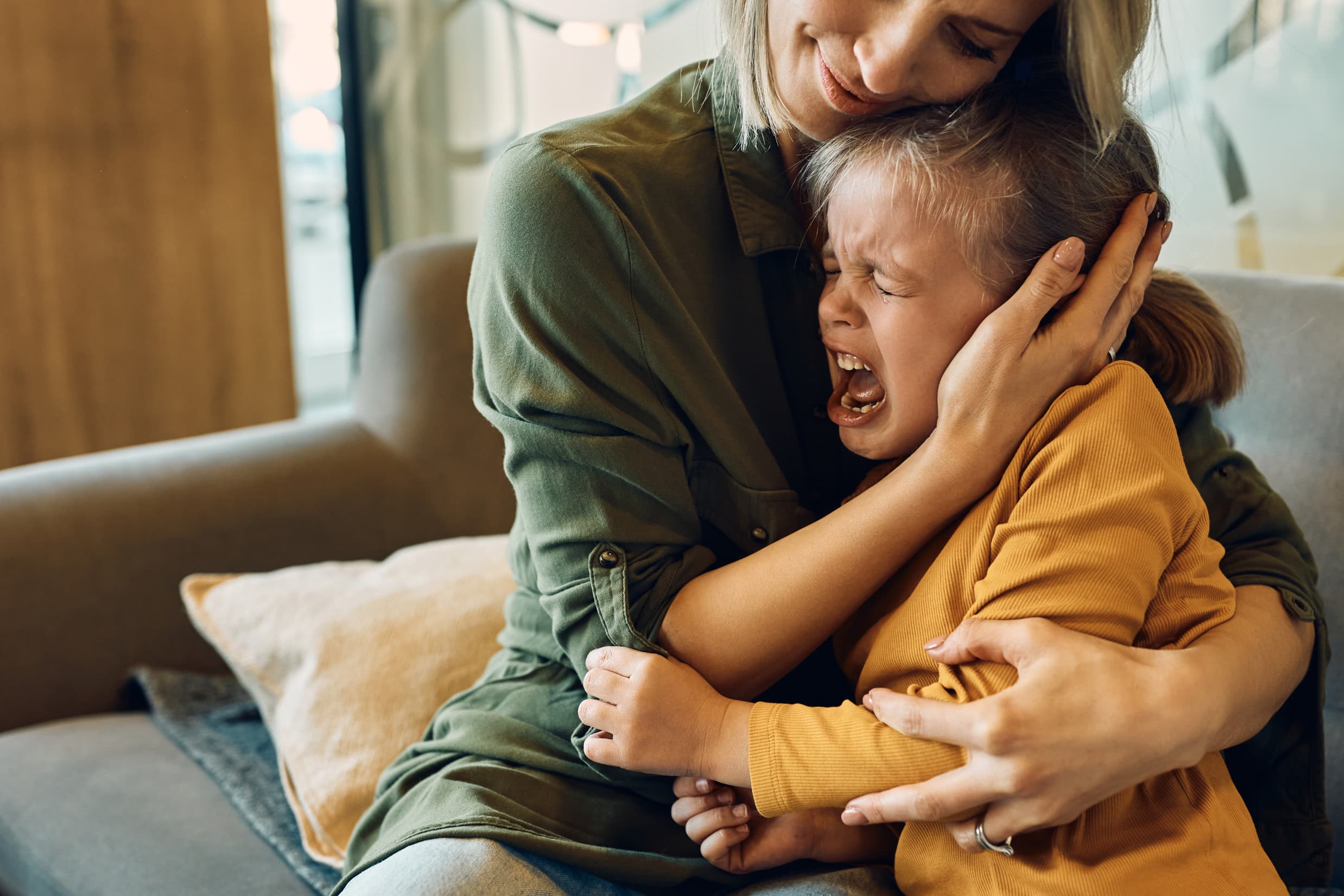 Parent sitting with crying child on couch