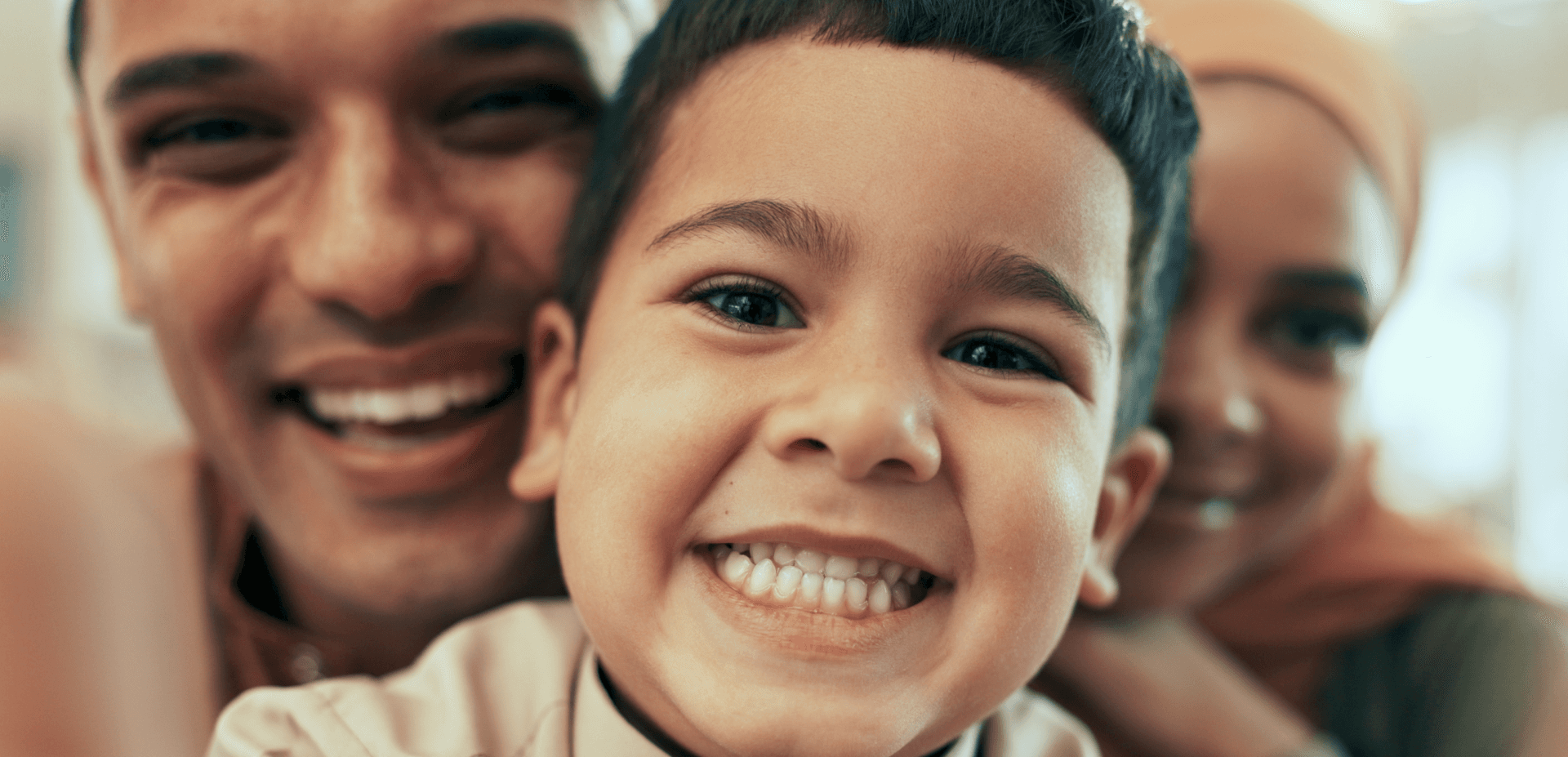Smiling young boy with parents behind him